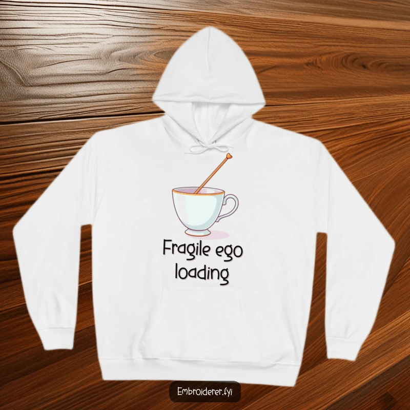 Funny hoodie featuring a teacup struggling to balance a massive needle on its rim, a comical image of effort.